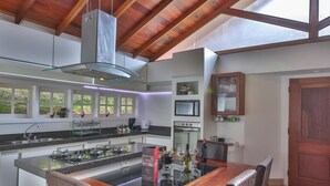 Una cocina moderna con una isla central, electrodomésticos integrados y techo de madera.