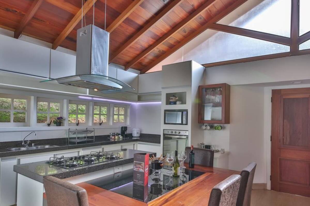 A modern kitchen with a central island, built-in appliances, and a wooden ceiling.