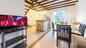 Una sala de estar moderna con televisor, comedor y cocina.