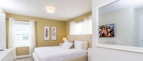 Un dormitorio con cama, mesita de noche, cómoda y espejo.