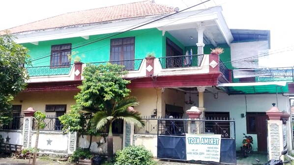 A two-story house with a green facade, a balcony, and a signboard advertising a rental property. - SPOT ON 93014 Griya Nautika Sukodono (Sidoarjo)