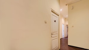 A hallway with a white door, a light switch, and a wall-mounted light fixture. - SPOT ON 93014 Griya Nautika Sukodono (Sidoarjo)