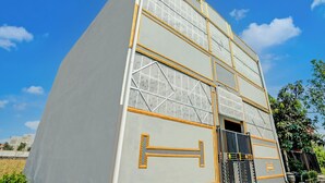 Un immeuble à plusieurs étages doté d’une architecture moderne, avec une entrée imposante, une porte noire et des éléments décoratifs dorés.