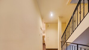 A hallway with a wooden floor, white walls, and a black metal railing on the right. - SPOT ON 93014 Griya Nautika Sukodono (Sidoarjo)