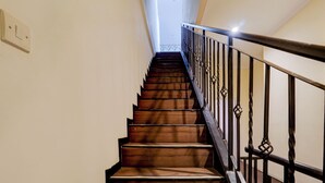 Un escalier en bois avec une rampe métallique menant à une porte située en haut.