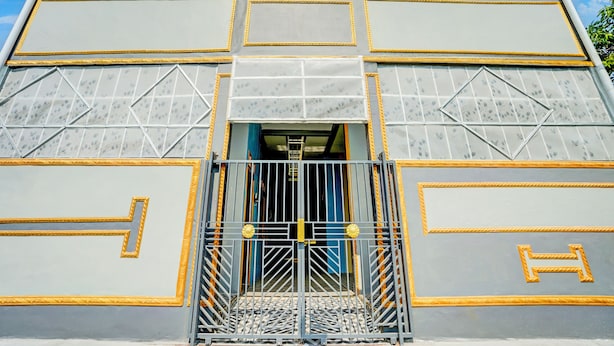 A building with a symmetrical facade, featuring a central entrance with a metal gate and a blue door. - SPOT ON 93014 Griya Nautika Sukodono (Sidoarjo)