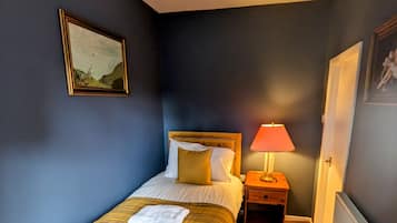 A bedroom with a bed, bedside table, lamp, and a radiator.