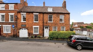 A two-story brick building with a white door and windows, a sign indicating 'Arlington House', and a parked car on the street. - Archway Guesthouse (Grantham)