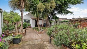 A garden with a pathway leading to a white building with a window. - Archway Guesthouse (Grantham)