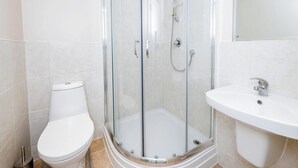 A bathroom with a glass-enclosed shower, a white toilet, and a white sink. - Archway Guesthouse (Grantham)