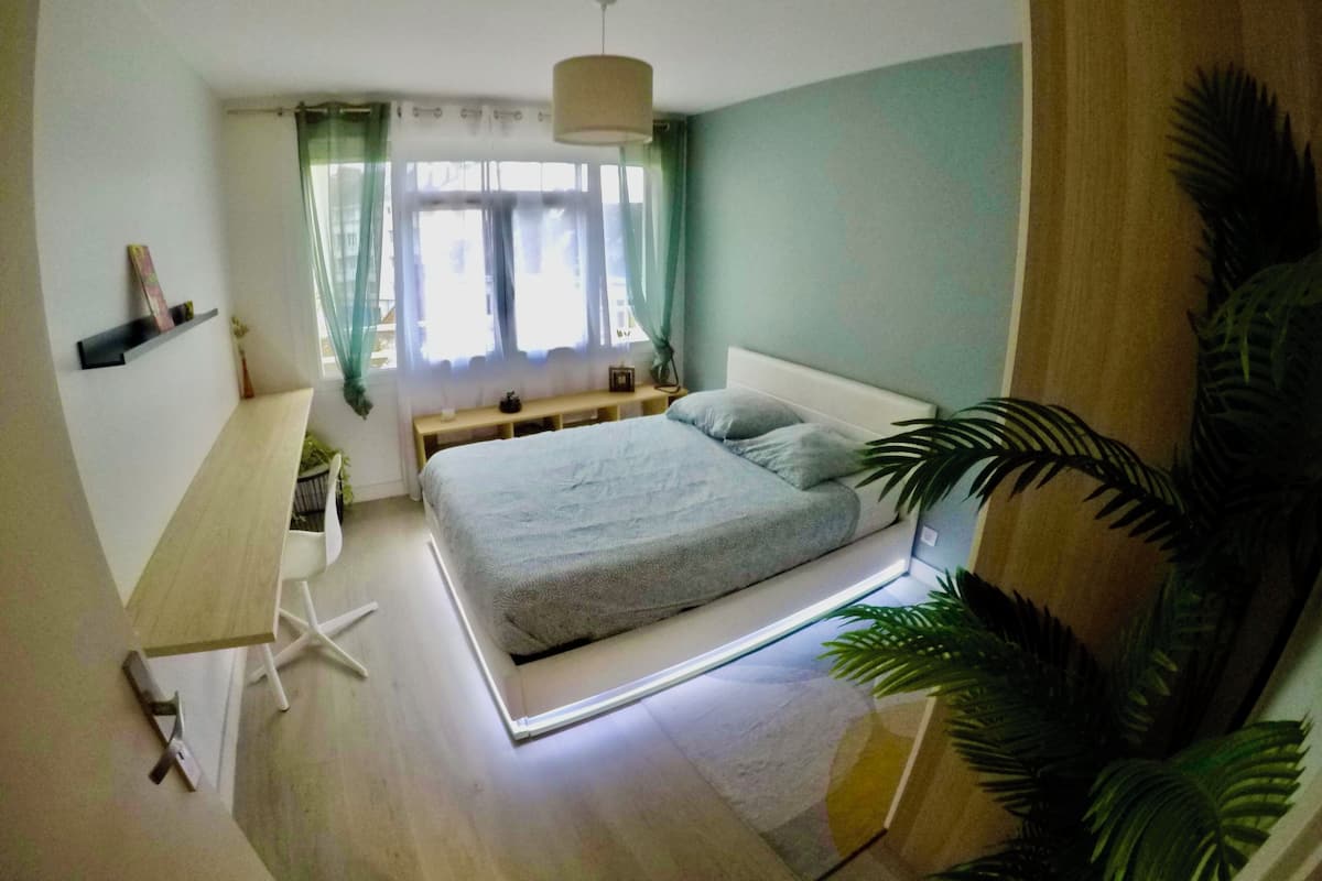 Un dormitorio con cama, escritorio y ventana con cortinas.
