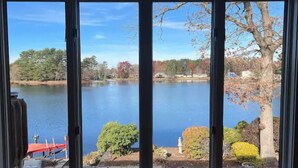 A view through a window of a lake with trees and a small dock. - Beautiful house on the lake (Coventry)