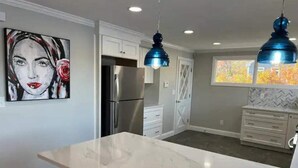 A modern kitchen with a marble countertop, stainless steel appliances, and pendant lighting. - Beautiful house on the lake (Coventry)
