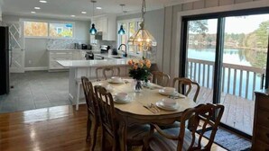 A modern kitchen with a central island, large windows, and a dining area with a view of a lake. - Beautiful house on the lake (Coventry)