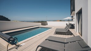 Une piscine sur le toit, dotée de chaises longues et offrant une vue sur l’océan.