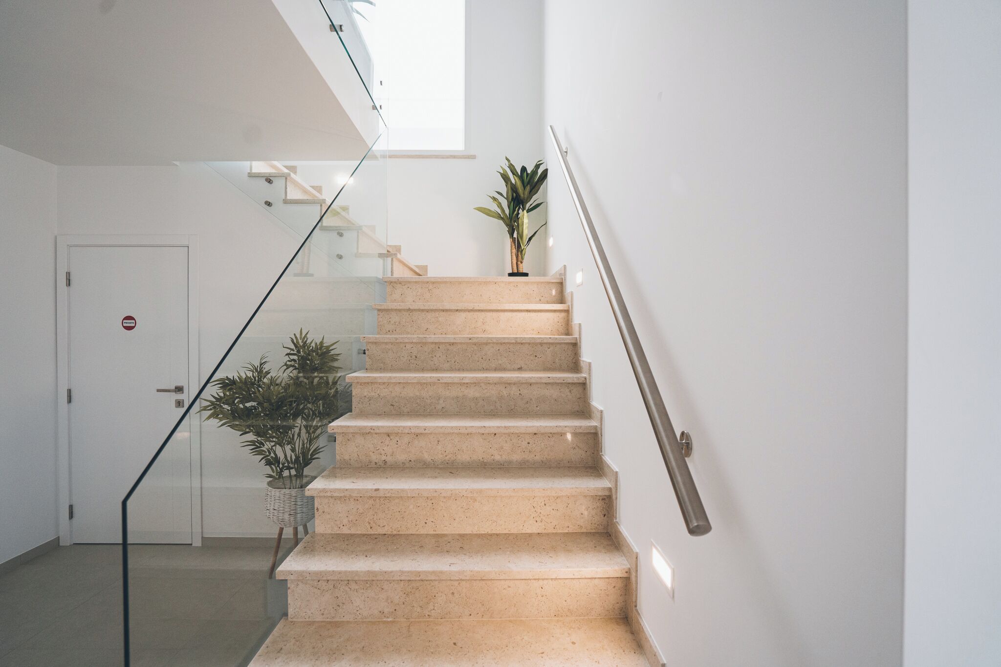 Un escalier avec une rampe, un pot de fleurs et une porte portant l’inscription « privé ».