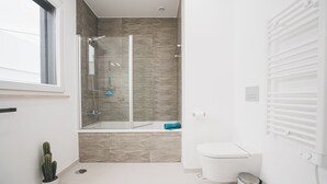 Une salle de bain moderne avec une douche en verre, des toilettes et une petite plante en pot.