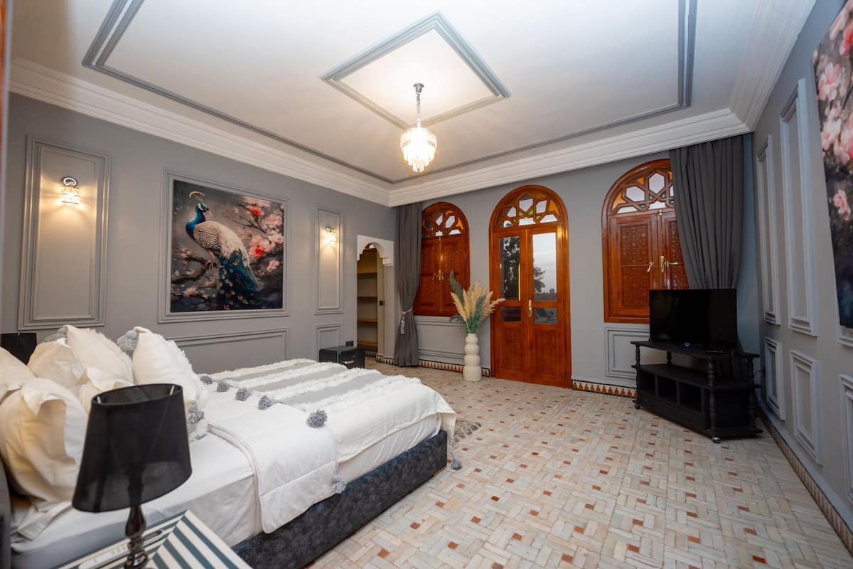 A spacious bedroom with a large bed, a television, and a decorative painting.