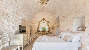 Une pièce comprenant un lit, une commode, une chaise, un miroir et un téléviseur.