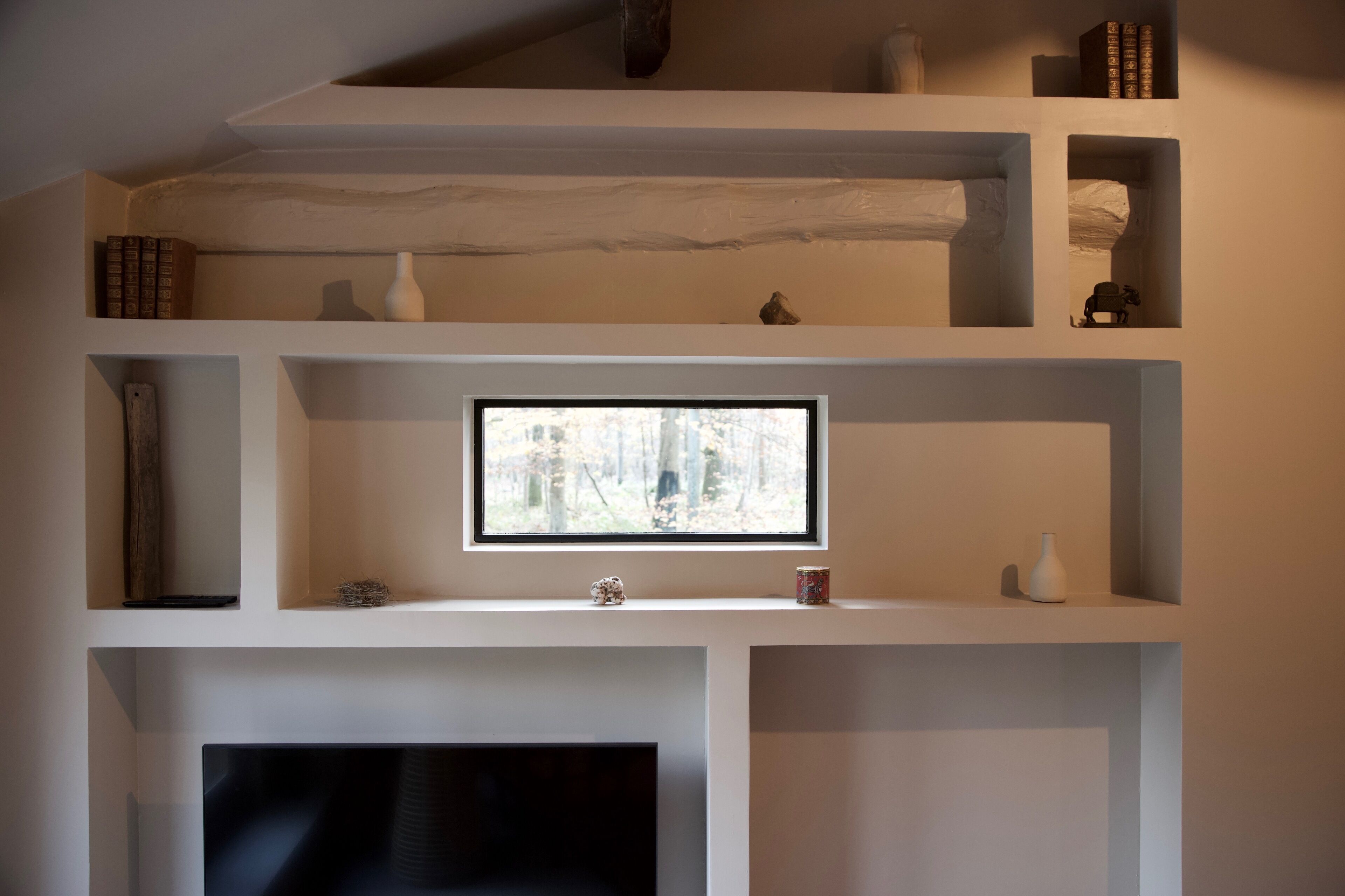 A modern interior with a fireplace, a television, and multiple shelves with decorative items.