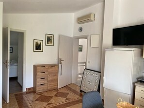 Cozy living space with a flat-screen TV, wooden cabinet, and air conditioning unit.