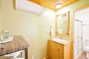 A bathroom with a wooden vanity, a sink, a mirror, and a shower.