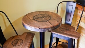 Una mesa redonda de madera con estructura metálica, acompañada de dos sillas a juego.