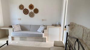 Un dormitori modern amb un llit gran, un sofà, una taula petita i decoracions murals.