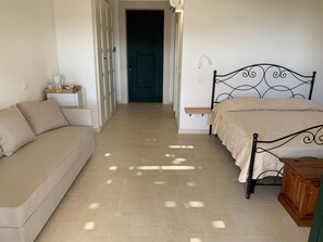 Une chambre à coucher avec un lit, un canapé, une table de chevet et une porte.