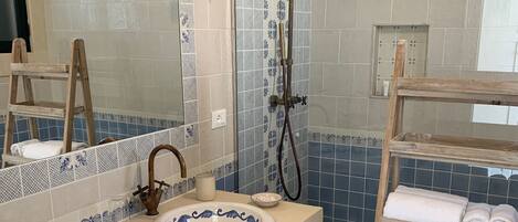 A bathroom with two sinks, a mirror, a shower, and a towel rack.