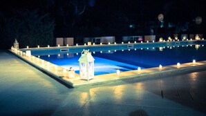 Una piscina amb una zona enrajolada i una filera de espelmes al costat.