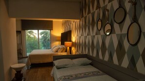 A hotel room with two beds, a sitting area, a window with a view of palm trees, and a geometric-patterned wall.