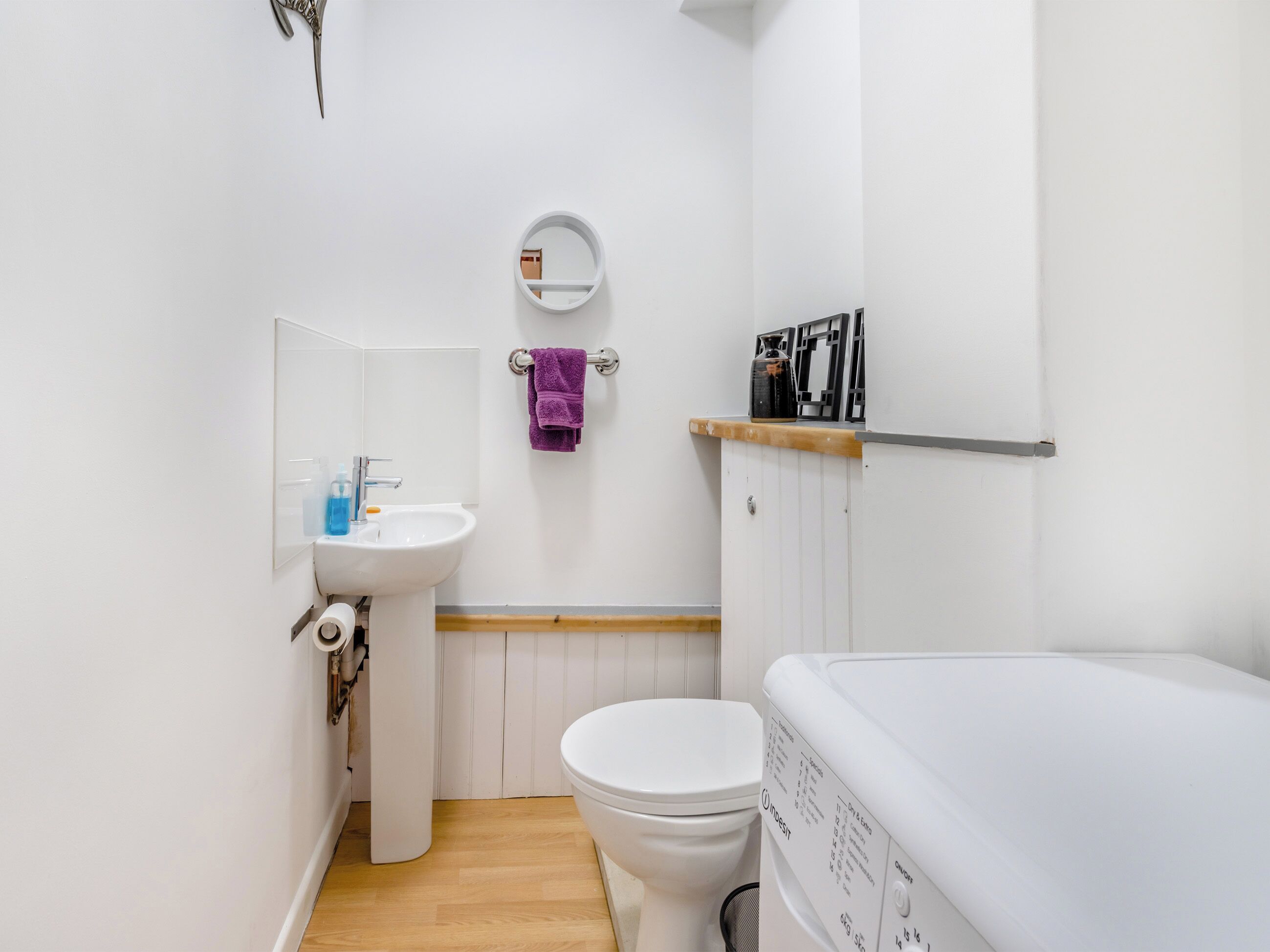 A compact bathroom with a white sink, toilet, and a small mirror.