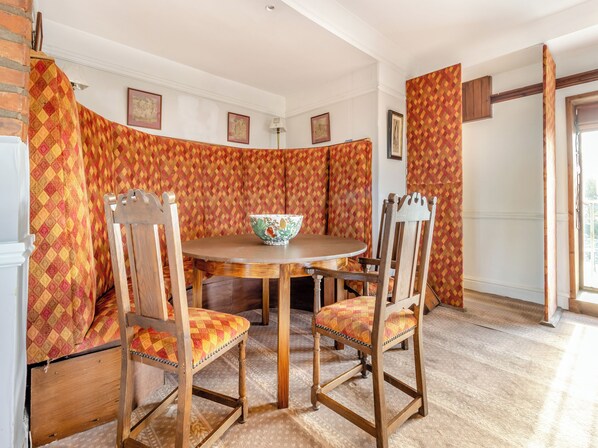 A dining area with a round table, two wooden chairs with cushioned seats, and a patterned curtain backdrop. - 2 bedroom accommodation in Llanon Aberystwyth (Llanon Aberystwyth)