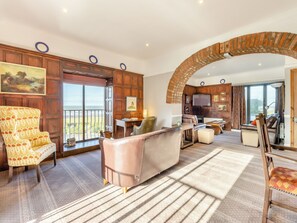 A spacious living area with a large arched brick fireplace, a comfortable seating arrangement, and a scenic view through the open door. - 2 bedroom accommodation in Llanon Aberystwyth (Llanon Aberystwyth)