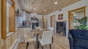 Eine moderne Küche mit weißen Schränken, Edelstahlgeräten und einem Essbereich mit Holztisch und weißen Stühlen.