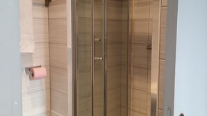 A modern bathroom with a glass-enclosed shower, a toilet, and a towel rack. - Hôtel Azur (Paris)
