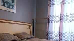 A bedroom with a patterned bedspread, a headboard, and a painting on the wall. - Hôtel Azur (Paris)