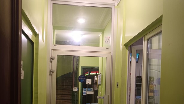 A hallway with patterned floor tiles, a glass door, and green walls. - Hôtel Azur (Paris)