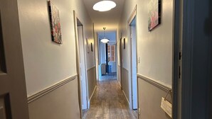 A hallway with wooden flooring, white walls, and a ceiling light. - The winged angels (MARCILLAC LA CROISILLE)