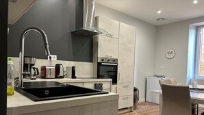 A modern kitchen with a central island, stainless steel appliances, and a dining area with a table and chairs. - The winged angels (MARCILLAC LA CROISILLE)