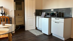 A compact kitchen with white cabinets, a microwave, a toaster, and a refrigerator.