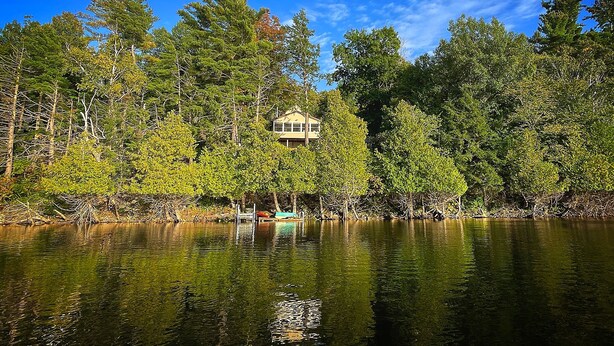 A house surrounded by dense forest and a calm lake. - Cassetta's View - Hickory Lake N.Y. (De Peyster)