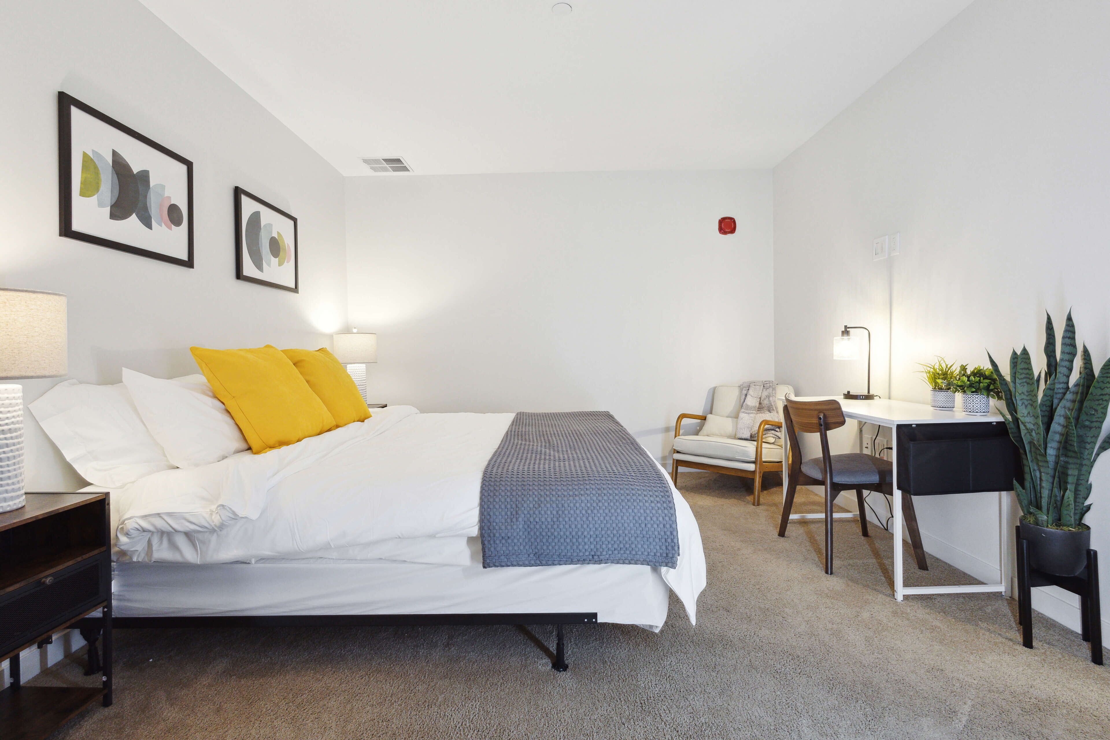 A modern hotel room with a neatly made bed, a desk, and a chair.