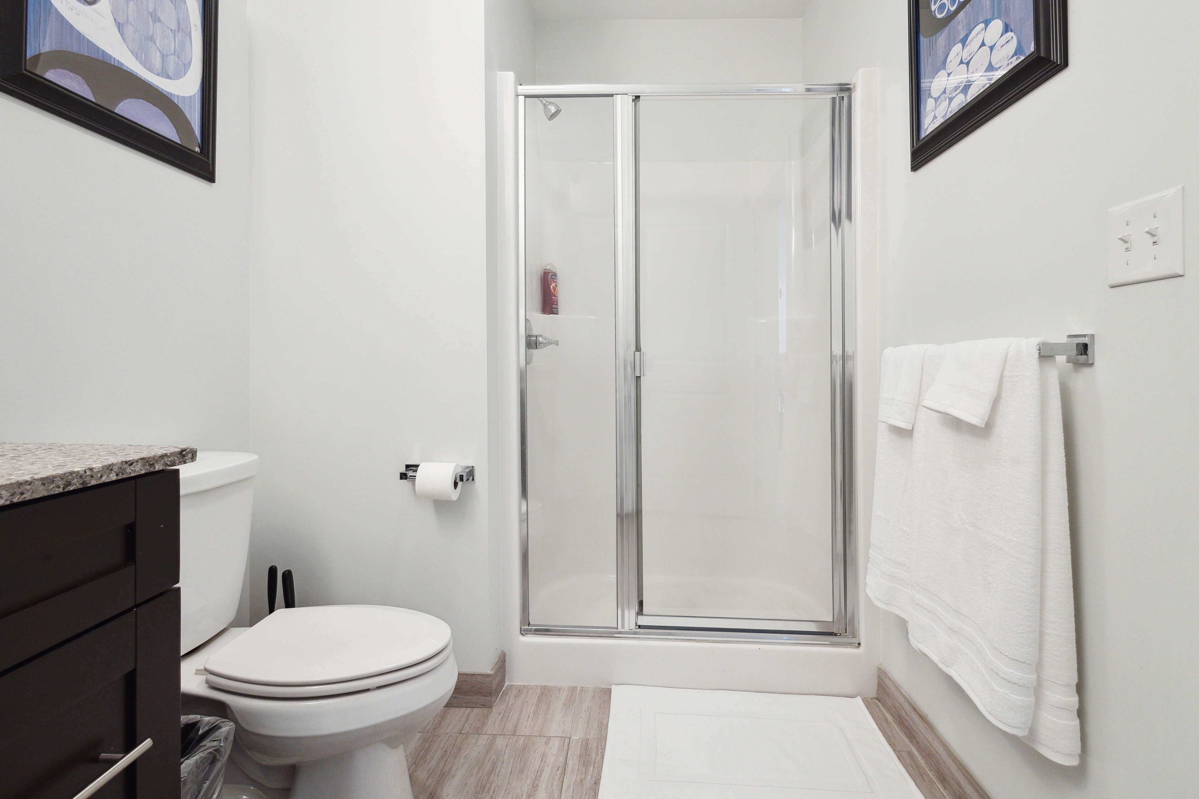 A modern bathroom with a glass-enclosed shower, a toilet, and a sink.