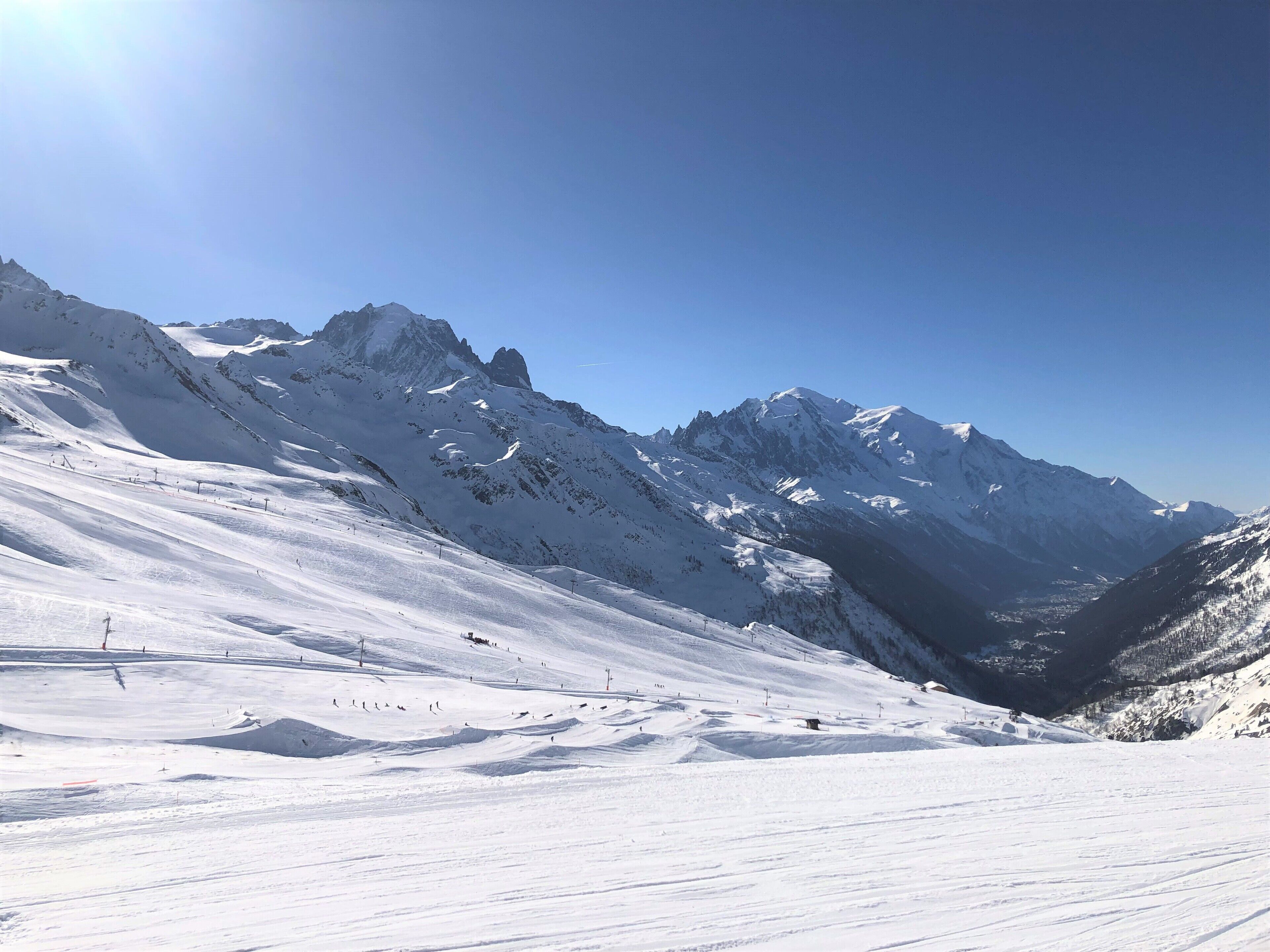 A snow-covered mountain landscape with ski slopes and a clear sky.