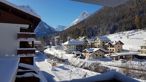 A snow-covered mountain resort with chalet-style buildings, a ski lift, and a clear view of the surrounding mountains.