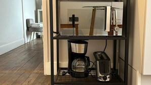 Eine Küche mit einer schwarzen Metallregaleinheit, die eine Kaffeemaschine, einen Toaster und einen Wasserkocher beherbergt.