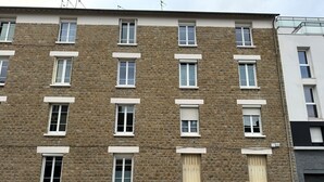 A multi-story building with a stone facade, multiple windows, and a flat roof. - L'escale (Rennes)