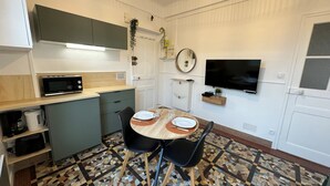A compact kitchen with a microwave, a sink, and a dining area with a table and chairs. - L'escale (Rennes)